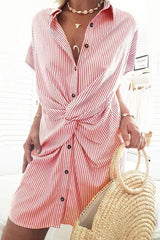 A woman wearing a red and white striped shirt dress with a twist knot detail.