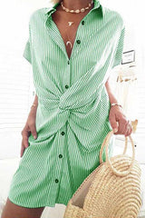 A woman wearing a green and white striped shirt dress with a twist knot detail.