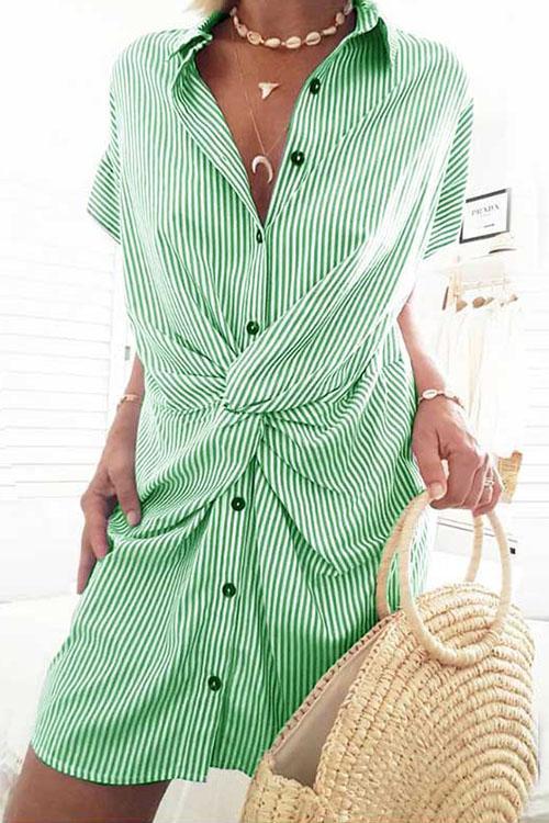 A woman wearing a green and white striped shirt dress with a twist knot detail.