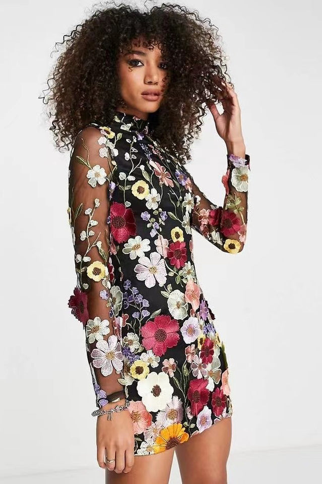 Side view of a woman in a black sheer mini dress adorned with 3D floral appliqués.
