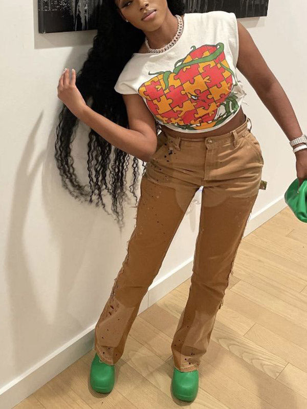 Woman posing with her hand on her hip in a white graphic t-shirt and brown distressed pants