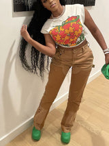 Woman posing with her hand on her hip in a white graphic t-shirt and brown distressed pants