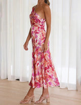 A woman poses in a pink and orange floral print one-shoulder satin dress, showing the side view.
