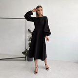 woman wearing a black midi dress with bishop sleeves and high heels