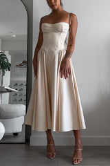 Woman wearing a cream bustier midi dress with a full pleated skirt and strappy heels.