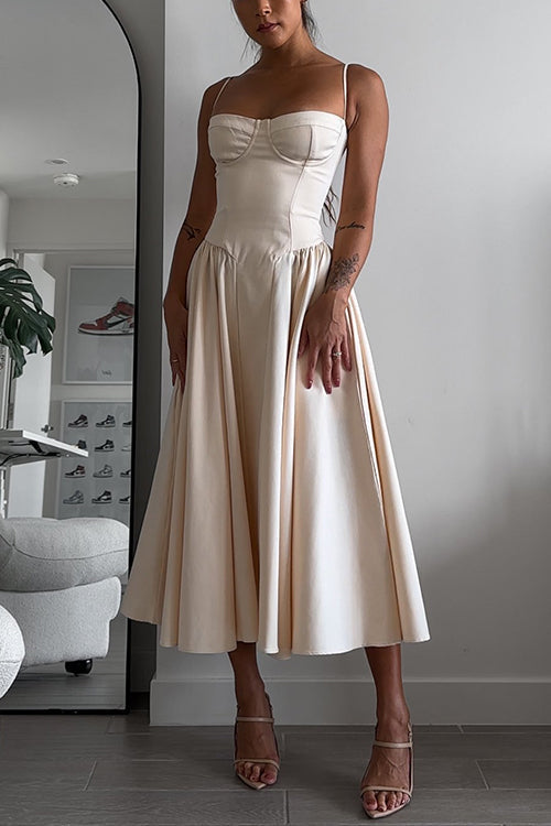Woman wearing a cream bustier midi dress with a full pleated skirt and strappy heels.