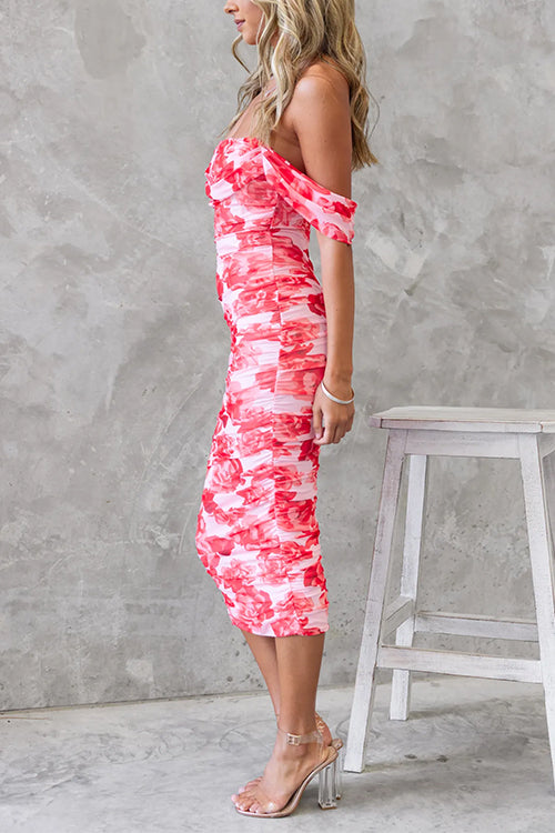 Side view of a woman in a pink and red floral print ruched midi dress