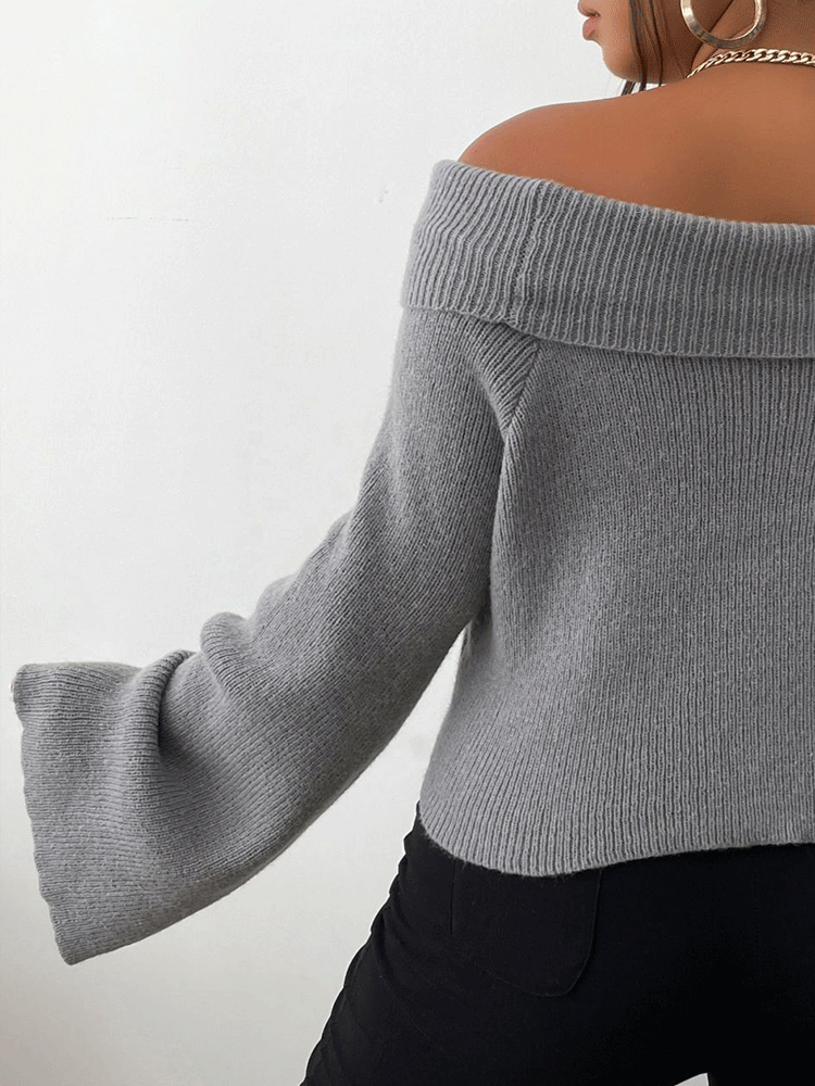 Side view of a woman wearing a gray off-the-shoulder sweater with bell sleeves and black pants.