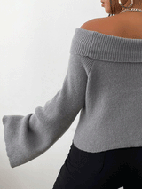 Side view of a woman wearing a gray off-the-shoulder sweater with bell sleeves and black pants.