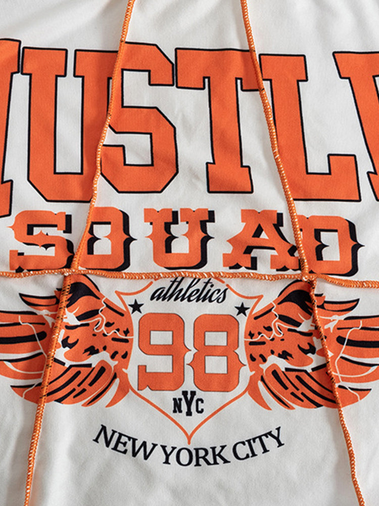 A close-up of the graphic print on a white cropped t-shirt, featuring orange text and wings.