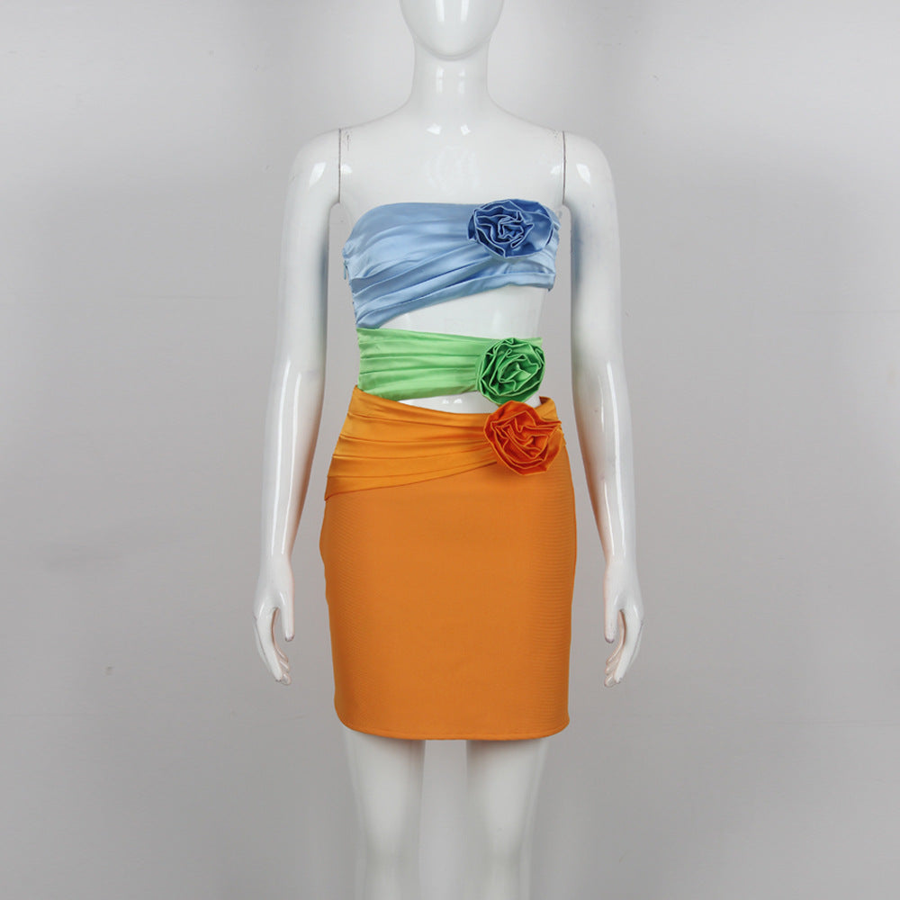 A mannequin displays a strapless dress with blue, green, and orange sections, adorned with flowers.