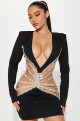 Close-up of a woman in a black mini dress with a plunging neckline and embellished sheer detailing.