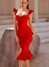 A woman wearing a form-fitting red dress with ruffled shoulders and a mermaid hem, posing outdoors.