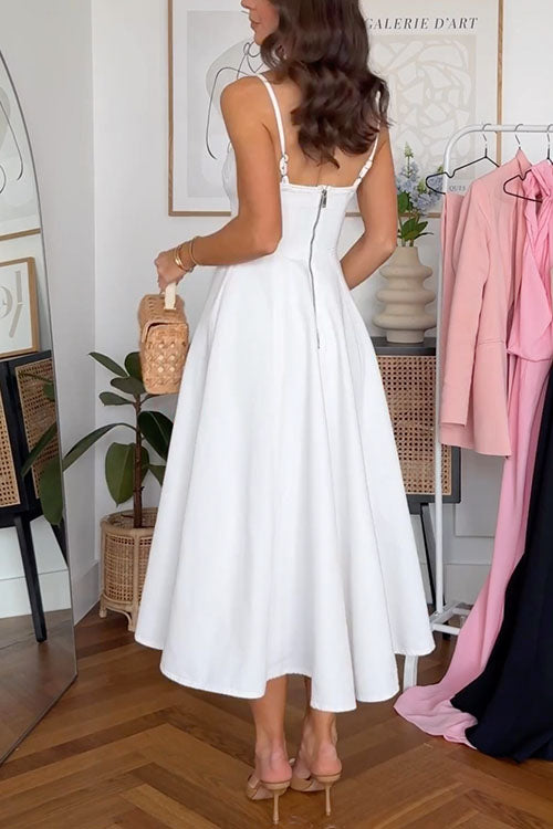 Back view of a woman wearing a white midi dress with a sweetheart neckline and a cut-out detail. The dress has a zipper closure.