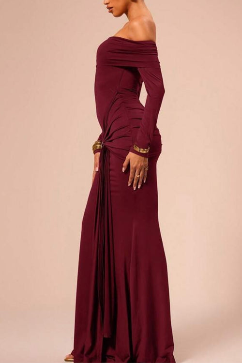 Side view of a woman in a long, off-the-shoulder maroon dress with ruched detailing and a gold buckle.