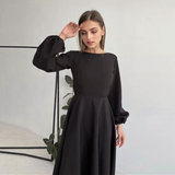 woman in a black midi dress with bishop sleeves posing
