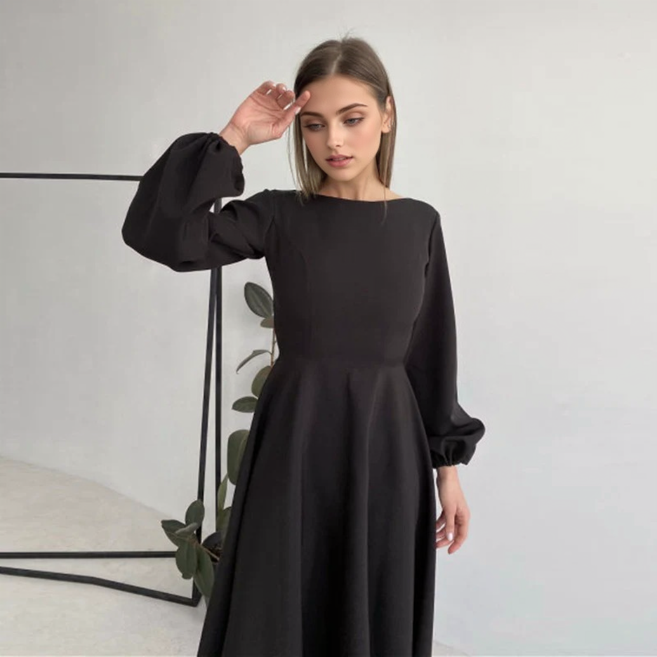 woman in a black midi dress with bishop sleeves posing