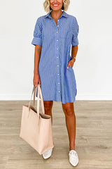 Woman wearing a blue and white striped shirt dress with white loafers and a large beige tote bag.
