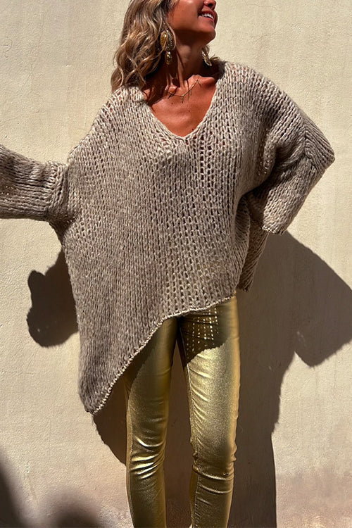 Close-up of a woman's outfit featuring a beige knit sweater and gold metallic pants.