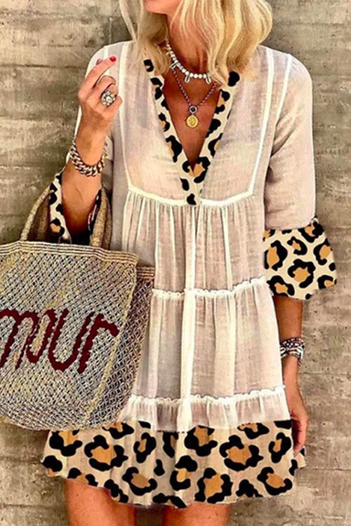 A woman wearing a white tiered dress with leopard print trim and bell sleeves.