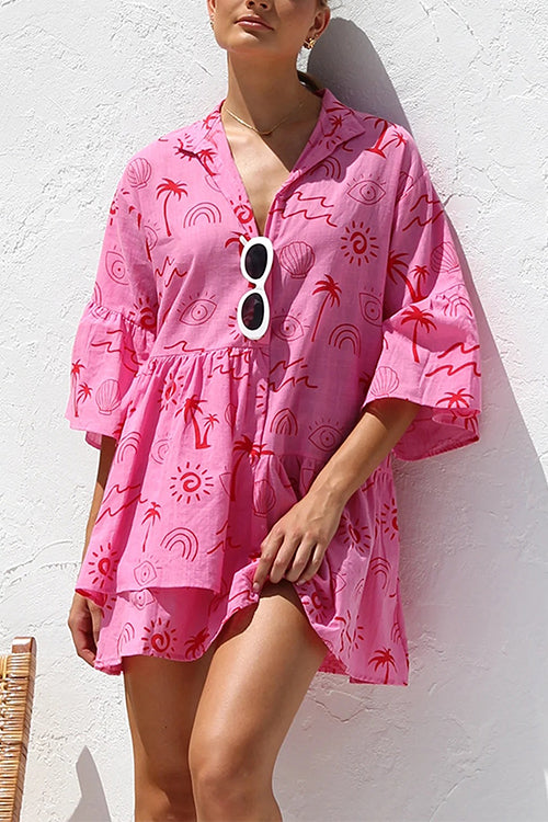 A woman in a pink tiered dress with a tropical print.