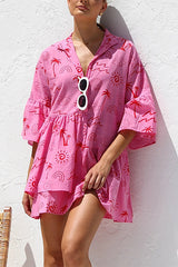 A woman in a pink tiered dress with a tropical print.