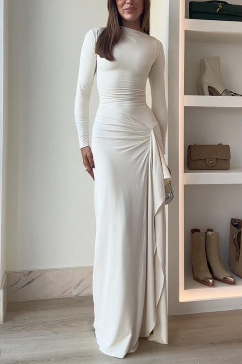 A woman in a long-sleeved ivory dress with a draped skirt.