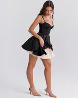 Woman in a black dress, walking, with a sweetheart neckline and a flared skirt with a tulle underskirt.