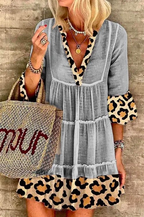 A woman wearing a gray tiered dress with leopard print trim and bell sleeves.