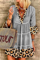 A woman wearing a gray tiered dress with leopard print trim and bell sleeves.