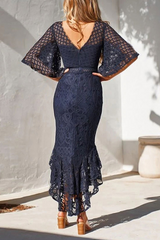 woman in a navy lace dress with bell sleeves and a ruffled high-low hem, back view