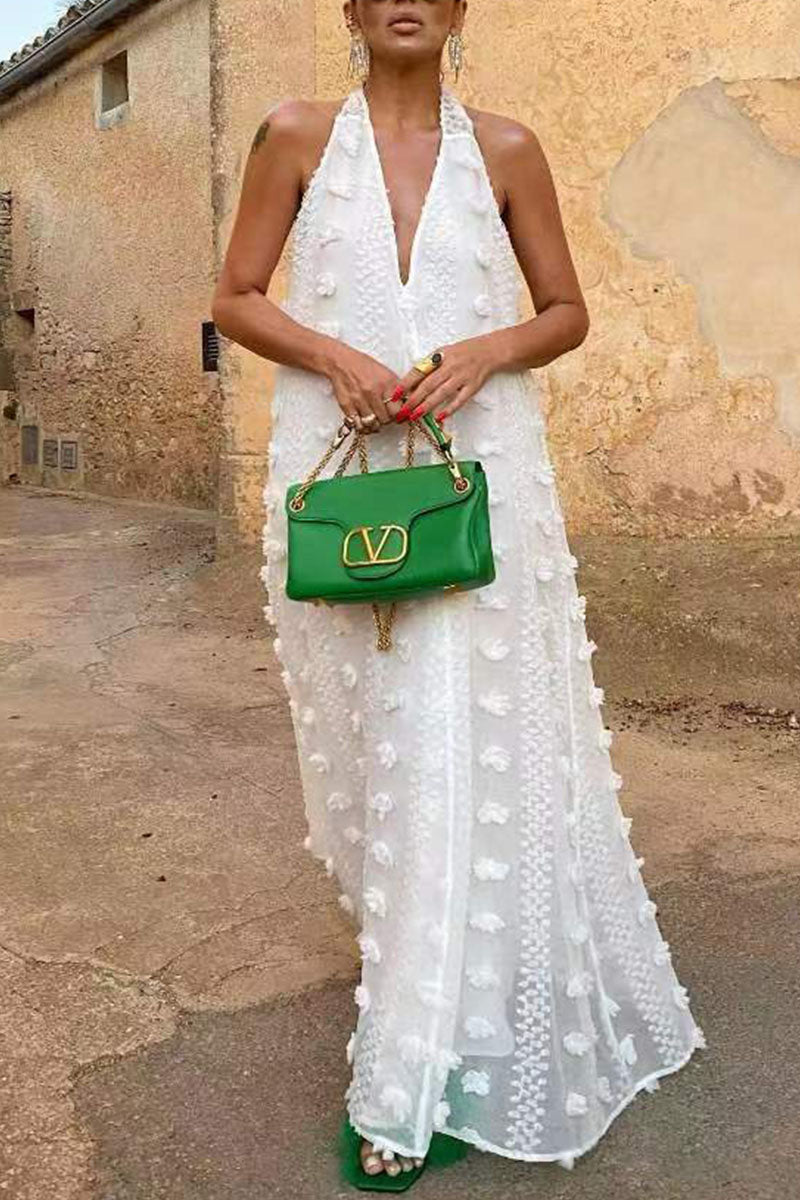 Woman posing in a white halter maxi dress and green furry sandals, holding a green handbag.