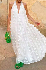 Woman twirling in a white sheer maxi dress with floral details and green accessories.