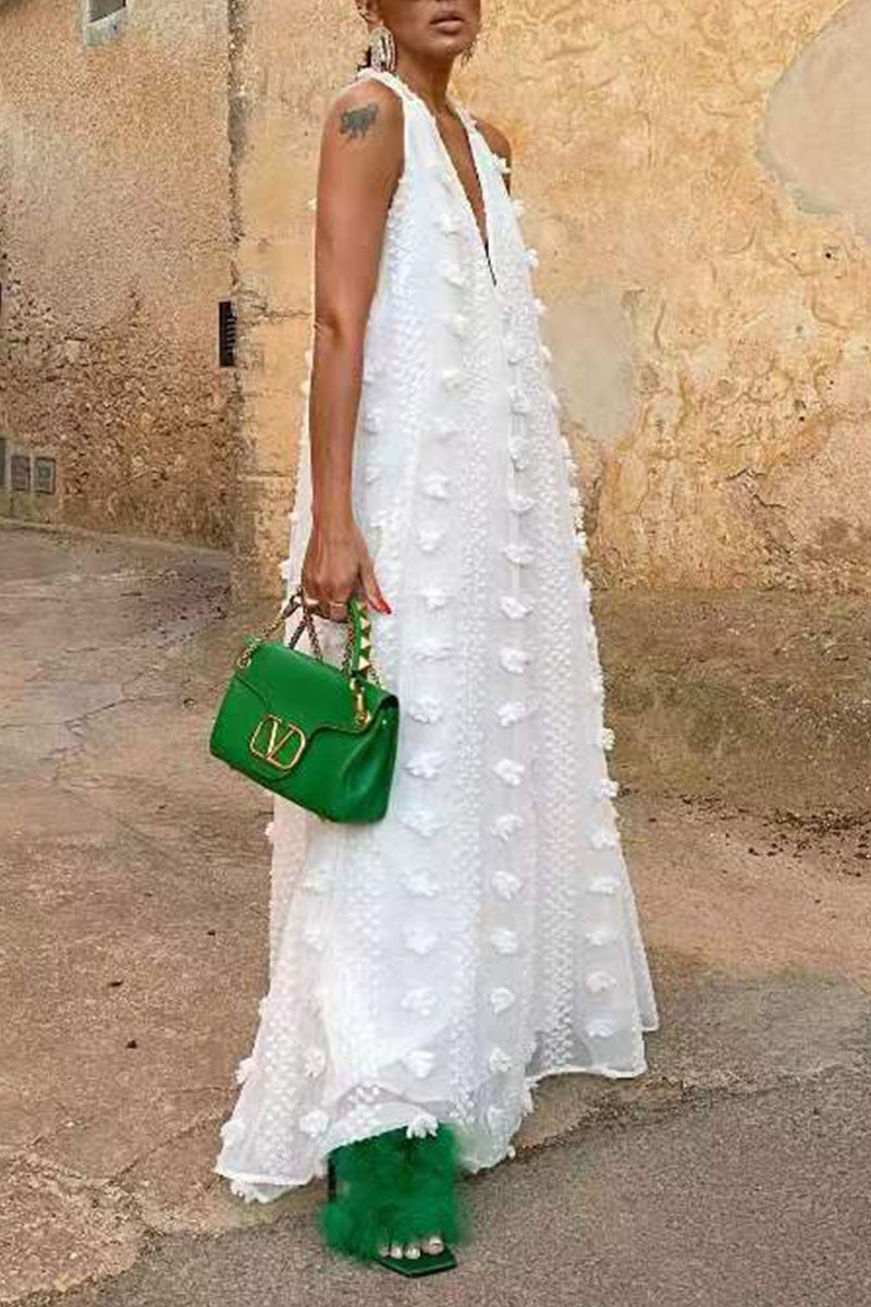 Side view of a woman in a white flowy maxi dress with a green purse.