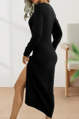 Woman wearing a black long-sleeve dress with a high slit and ruching on the side, showing the back of the dress.