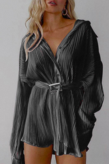 Woman wearing a black pleated long-sleeved shirt dress with a belted waist.