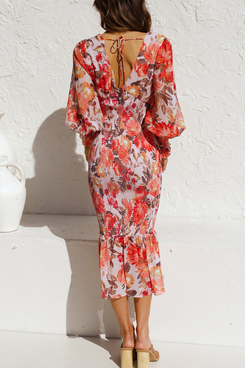 back view of a woman in a red and orange floral print dress with balloon sleeves and a ruffled hem