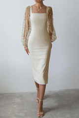 A model showcases a cream dress with a fitted silhouette and dramatic sheer sleeves adorned with delicate patterns.