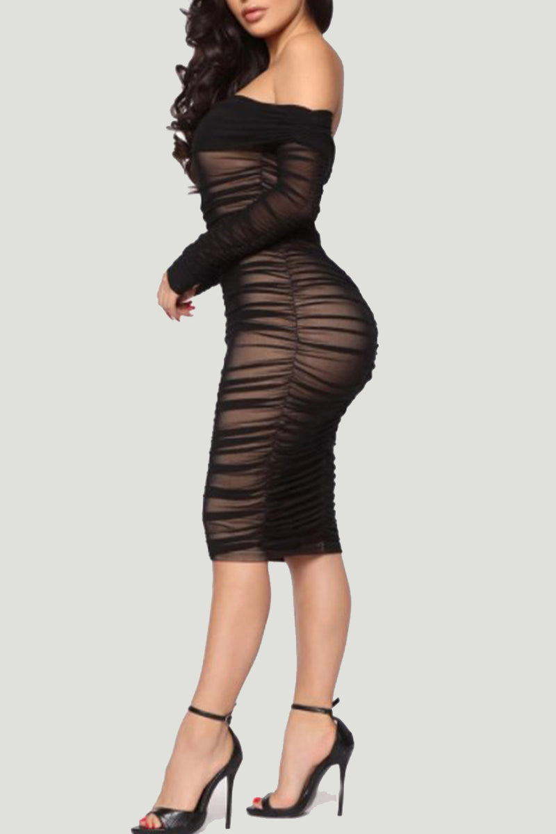 Woman wearing a black off-the-shoulder ruched mesh dress with sheer long sleeves and black high heels, shown from the side