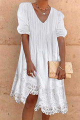 woman wearing a white short-sleeved dress with lace trim and a v-neck