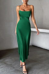 Front view of a woman in a green satin slip dress with spaghetti straps and a square neckline, accessorized with necklaces and earrings.