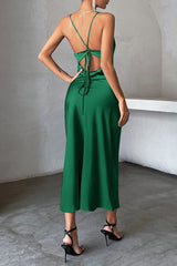 Back view of a woman wearing a green satin slip dress with a backless design and adjustable tie back.