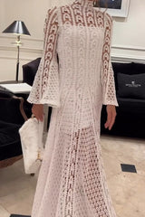 Woman standing in a white crochet dress holding a white furry clutch