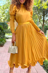 woman in a yellow pleated dress with puffy sleeves