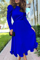 woman in a royal blue pleated dress with puffy sleeves