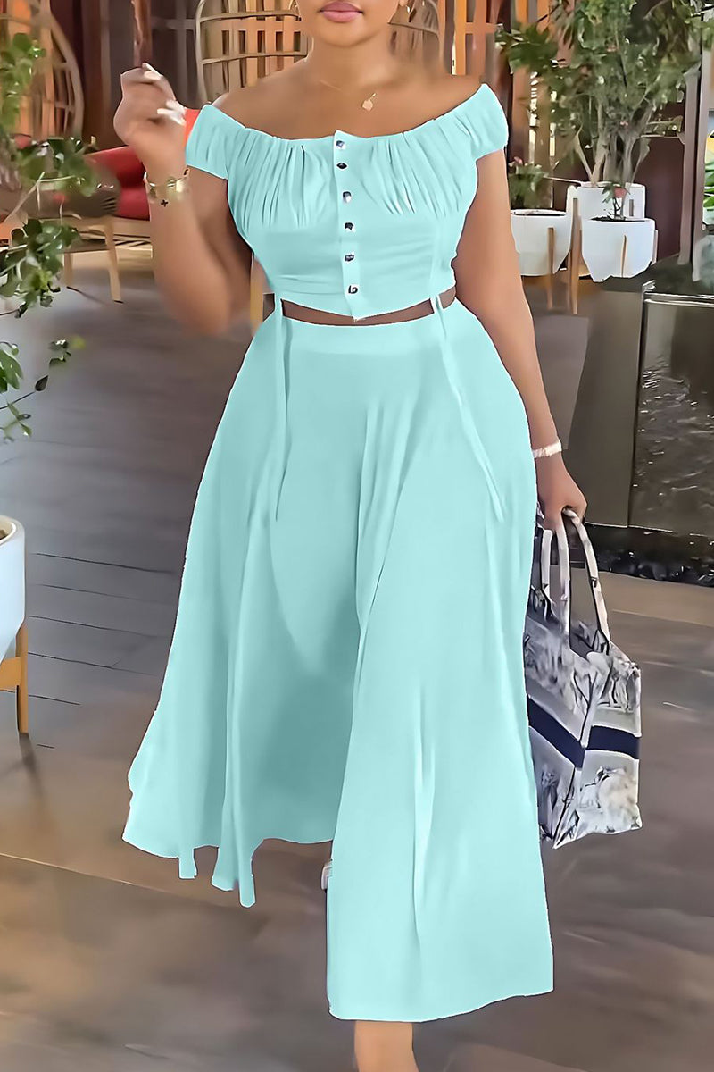 Woman wearing a mint green off-the-shoulder ruched top and matching wide-leg pants, holding a tote bag.