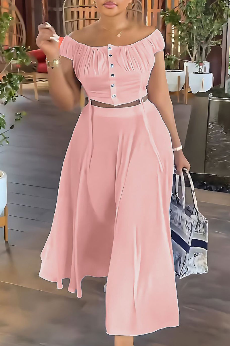 Woman wearing a pink off-the-shoulder ruched top and matching wide-leg pants, holding a tote bag.