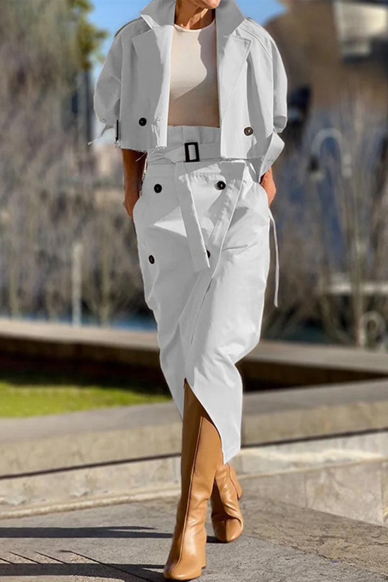 Woman wearing a white cropped jacket and matching asymmetrical skirt with tan boots