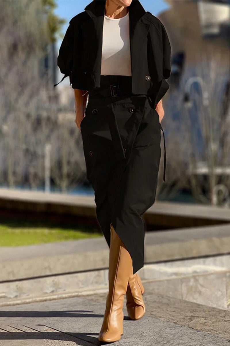 Woman wearing a black cropped jacket and matching asymmetrical skirt with tan boots