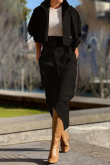 Woman wearing a black cropped jacket and matching asymmetrical skirt with tan boots